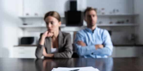 couple sitting next to each other behind divorce papers and wedding rings