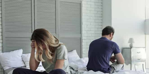 couple sitting on opposite ends of a bed