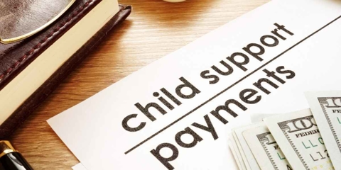 Papers that read "child support payments" with a few hundred dollars resting in the corner